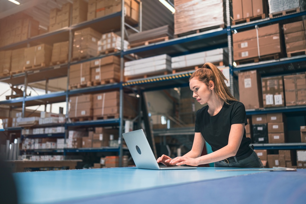 Warehouse employee managing inventory data on computer using ERP software