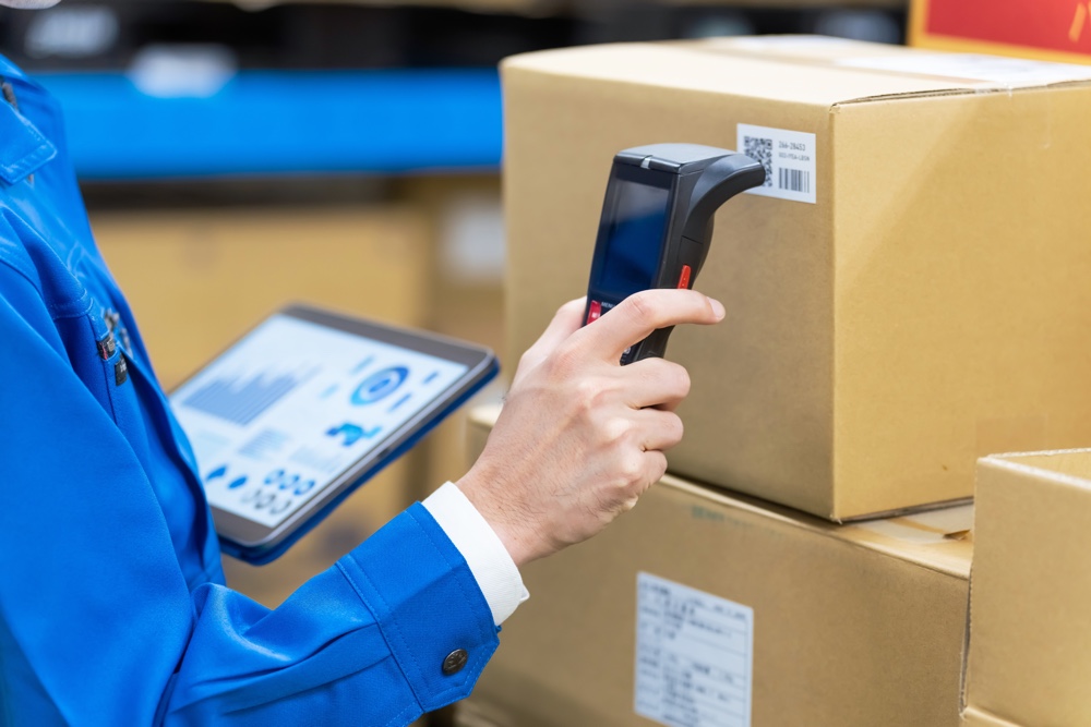 Warehouse worker scanning boxes for inventory tracking with ERP system